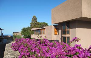 a building with purple flowers in front of it at Centro Vacanze Cugnana Verde in Marina di Portisco