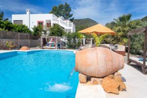 una piscina con sombrilla junto a una casa en Villa Felisa, en Sant Josep de sa Talaia