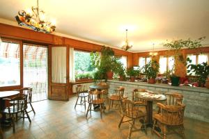 un comedor con mesas, sillas y plantas en Hotel Edelweiss en Villeneuve