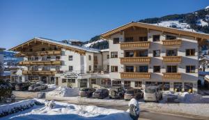 ein großes Gebäude mit Autos auf einem Parkplatz in der Unterkunft Hotel Bichlingerhof in Westendorf