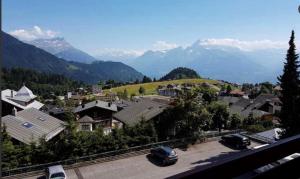 a town with cars parked in a parking lot with mountains at Apartment Leysin - Swiss Alps - Fully Renovated ! in Leysin