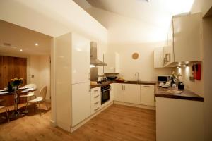 a kitchen with white cabinets and a dining room at The Stables 3 in Nefyn