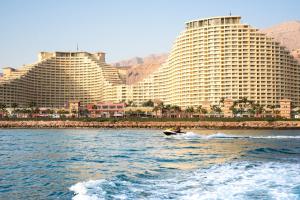 a boat in the water in front of two large buildings at Porto Sokhna Beach Resort in Ain Sokhna