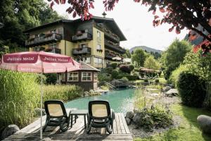 ein paar Stühle und ein Regenschirm neben einem Teich in der Unterkunft Garni Haus Sonnleitn - Adults only in Fuschl am See