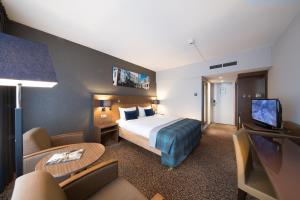 a hotel room with a bed and a flat screen tv at Bilderberg Garden Hotel in Amsterdam