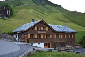 a large wooden house with a hill in the background at Alm – Chalet Domig in Damuls
