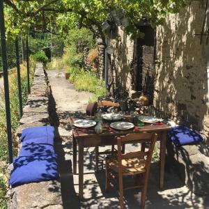 a table in the shade of a stone wall with a table sidx sidx at Les Volets Verts in Miraval-Cabardès