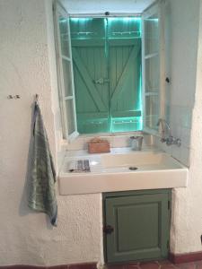 a bathroom sink with a green cabinet and a mirror at Les Volets Verts in Miraval-Cabardès