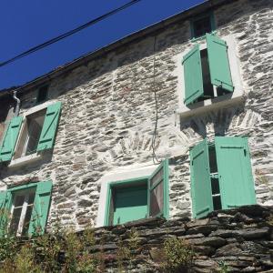an old stone building with green shuttered windows at Les Volets Verts in Miraval-Cabardès