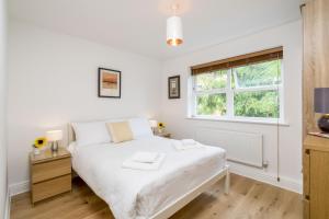 a white bedroom with a bed and a window at Sunny 2BR apt in the heart of Vauxhall, by subway in London
