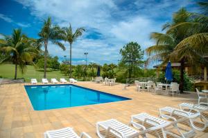 a pool with chairs and tables and palm trees at Otho Hotel Convention & SPA in Itu