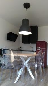 リーヴァ・デル・ガルダにあるAppartamento Brioneのダイニングルームテーブル(透明な椅子、照明器具付)
