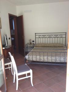 ポッジョ・ムレッラにあるCasa Saturniaのベッドルーム(ベッド1台、椅子、テレビ付)