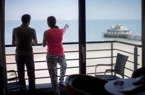 zwei Menschen, die aus einem Fenster auf den Ozean blicken in der Unterkunft Hotel Riant-Séjour by WP Hotels in Blankenberge