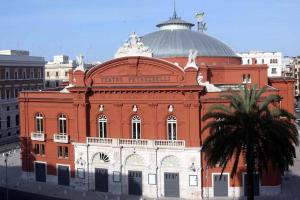 a large orange building with a palm tree in front of it at Giuseppe & Greta in Bari