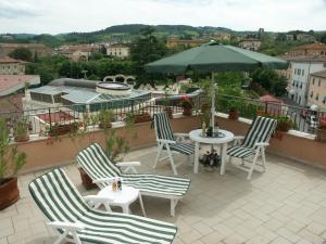 a patio with chairs and a table and an umbrella at Albergo Livorno in Casciana Terme