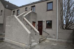 un edificio de ladrillo con una escalera delante de una puerta en Castleyards Apartment 1, en Kirkwall