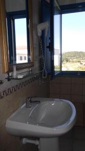 a white sink in a bathroom with two windows at Hotel Baia Cea in Bari Sardo
