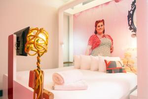 a woman is standing behind a bed in a room at The Corner London City in London