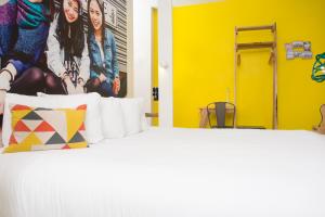 a bedroom with a white bed with a yellow wall at The Corner London City in London