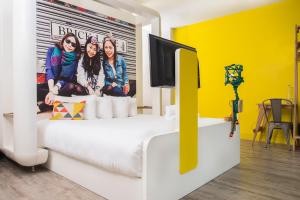 um quarto com uma cama branca e uma parede amarela em The Corner London City em Londres