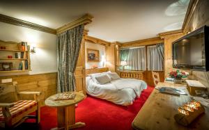 a living room with a couch and a tv at Hotel & Spa Le Dahu in Morzine