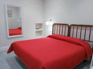 a bedroom with a red bed and a mirror at Pension Silene Orotava in La Orotava