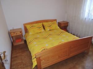 a bed with a yellow comforter and two night stands at Apartma Lesjak 1 in Bovec