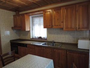 a kitchen with wooden cabinets and a sink and a table at Apartma Lesjak 1 in Bovec