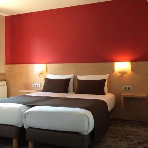 a bedroom with a large bed with a red wall at La Clef des Champs - Proche Colmar in Biesheim