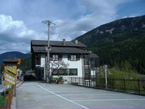 a building with a parking lot in front of a mountain at Residence Hotel Montechiara in Baselga di Pinè