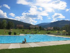 a person sitting in a swimming pool with people in a field at Apartment.Kirche in Sankt Georgen ob Murau
