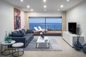 a living room with a blue couch and a view of the ocean at Villa Mar Azul in Salema +18 photos