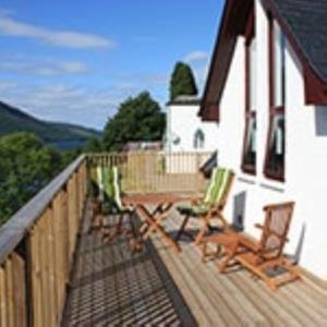 a deck with rocking chairs and a house at Letterfinlay Lodge House in Letterfinlay