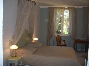 a bedroom with a bed with two lamps and a window at Le Platane in Lafrançaise