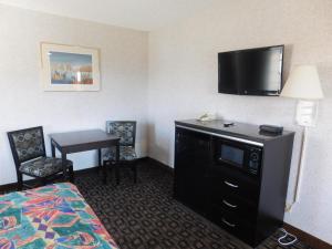 a hotel room with a bed and a desk with a television at Inns of California Salinas in Salinas