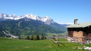 eine Hütte auf einem Hügel mit Bergen im Hintergrund in der Unterkunft Apartment Xenia in Garmisch-Partenkirchen