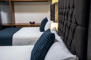 a bedroom with two beds with blue and white pillows at Hotel Casa Aurora in Quer&eacute;taro