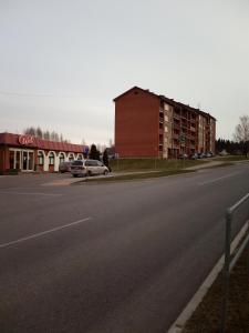 an empty road next to a red building and a building at Kalbakas Apartamenti in Smiltene