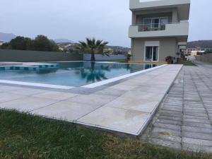 a swimming pool in front of a house at Holiday Luxury Villas in Kalamaki Heraklion