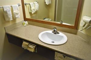 
a bathroom sink with a mirror above it at Sigma Inn & Suites Hudson's Hope in Hudson Hope
