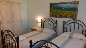 two beds in a bedroom with a painting on the wall at Hotel Baia Cea in Bari Sardo