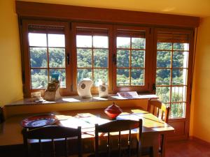 d'une salle à manger avec une table, des chaises et des fenêtres. dans l'établissement Apartamentos Rurales Veredas, à Santa Eulalia de Oscos