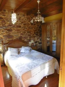 - une chambre avec un grand lit dans un mur en pierre dans l'établissement Apartamentos Rurales Veredas, à Santa Eulalia de Oscos