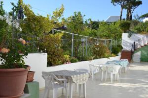 eine Terrasse mit weißen Tischen, Stühlen und Pflanzen in der Unterkunft Appartamenti Villa Annunziata in Ischia