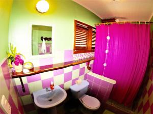 a bathroom with a sink and a toilet and pink curtains at Cafe de la Suerte in Pavones
