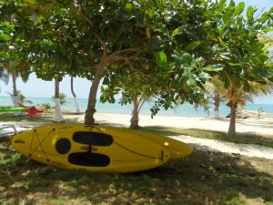 a yellow kayak sitting under a tree on the beach at Condominio Milagros Coveñas in Coveñas