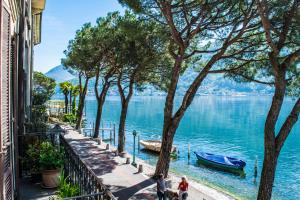 two people and two dogs walking on a sidewalk next to the water at Al Battello in Morcote