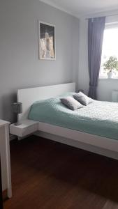 een witte slaapkamer met een bed en een raam bij Apartament Papaj in Giżycko