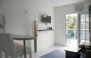 een witte woonkamer met een tafel en een tv aan de muur bij El Cabarete Spa Resort all-Inclusive in Cabarete